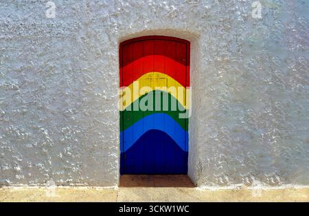 Façade blanche avec porte peinte arc-en-ciel dans un village de pêcheurs andalou, Espagne. Image horizontale avec amplement d'espace pour le texte, la diversité et le tourisme conc Banque D'Images