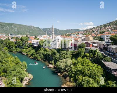 Photo de drone aérien de Stari Most à Mostar montrant la mosquée Koski Mehmed Pacha, la rivière Neretva avec des bateaux de vitesse touristiques rouges, la vieille ville Banque D'Images