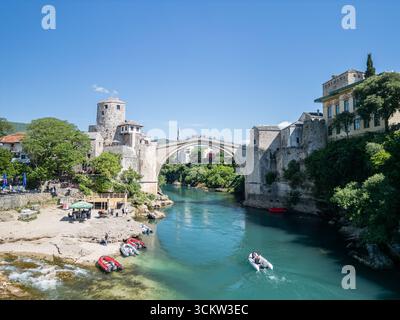 Photo drone du vieux pont à Mostar, Bosnie-Herzégovine, avec des bateaux touristiques sur la rivière Neretva en contrebas, et la mosquée Koski Mehmed Pacha Banque D'Images