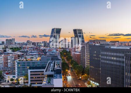 Vue aérienne de Madrid au crépuscule, regardant du nord au sud, avec la ville baignée de tons crépusculaires chauds. Les tours emblématiques de Puerta de Europa, connues pour Banque D'Images