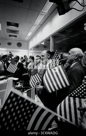 HOUSTON, TEXAS, États-Unis - 24 juillet 1969 - les responsables de la NASA et du Centre spatial habité (MSC) se joignent aux contrôleurs de vol, dans la salle de contrôle des opérations de mission (MOCR) du Centre de contrôle de mission (MCC), pour célébrer le succès de la mission d'atterrissage lunaire Apollo 11. Identifiables dans l'image, à partir du premier plan, sont Dr Robert R. Gilruth, directeur du MSc ; George M Low, directeur, Apollo Spacecraft Program, MSc ; Dr Christopher C Kraft Jr., MSc Directeur des opérations de vol ; Lt Gen Samuel C Phillips (avec des lunettes, regardant vers le bas), Directeur du programme Apollo, Bureau o Banque D'Images