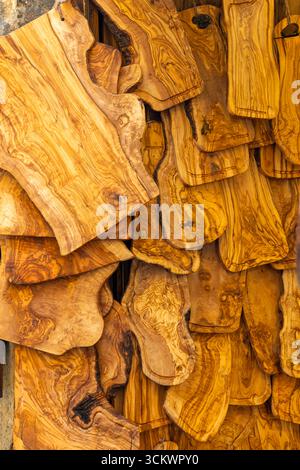 Différentes tailles de planches à découper en bois d'olivier accrochées dans un magasin, mettant en valeur leurs grains uniques et leurs tons chauds Banque D'Images