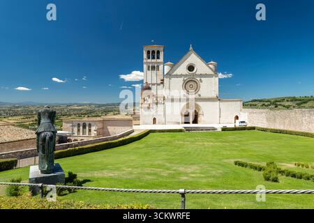 Basilica di San Francesco d'assise avec statue équestre et campagne ombrienne en arrière-plan sur une journée d'été ensoleillée Banque D'Images
