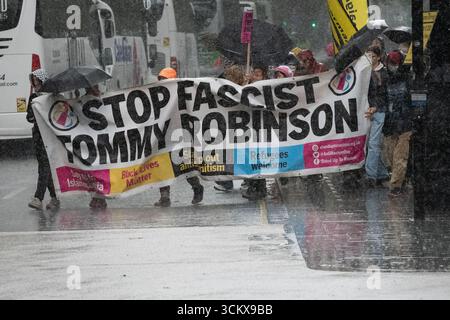 Londres, Royaume-Uni. 13 septembre 2025. Des pluies torrentielles tombent brièvement alors que des manifestants portant une grande bannière indiquant « Stop fasciste Tommy Robinson » prennent part à la « Marche contre le fascisme » qui a vu des milliers d'anti-racistes marcher de Russell Square à Whitehall. La marche était une contre-protestation contre celle organisée par le nationaliste d'extrême droite 'Tommy Robinson' - de son vrai nom Stephen Yaxley-Lennon. Crédit : Ron Fassbender/Alamy Live News Banque D'Images