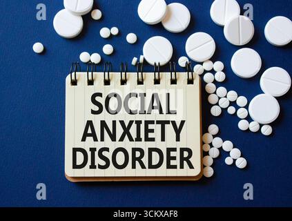 Symbole du trouble d'anxiété sociale. Mots conceptuels trouble d'anxiété sociale sur ordinateur portable. Beau fond bleu profond avec des pilules. Santé et social an Banque D'Images