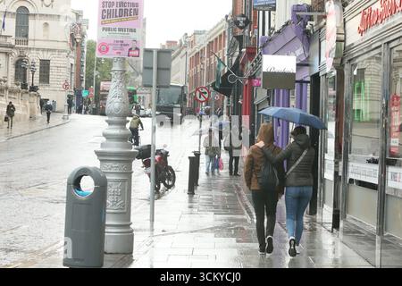 Dublin, Irlande - 12 septembre 2025 - Un couple avec parapluie marche sur le sentier de Dame Street pendant les précipitations dans le centre-ville de Dublin Banque D'Images