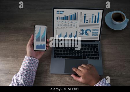 Concept de tableau de bord de données d'entreprise, montrant des graphiques analytiques sur ordinateur portable et smartphone. Espace de travail professionnel avec graphiques pour la finance, le marketing et les PER Banque D'Images