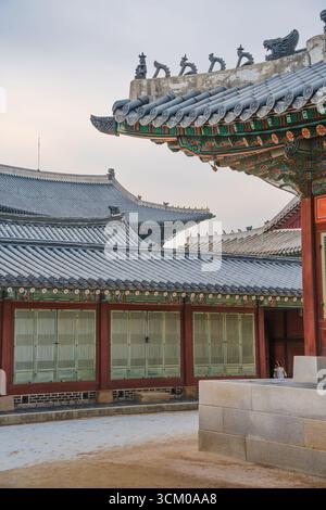 Vue détaillée de la cour du palais de Gyeongbokgung à Séoul avec des toits de tuiles ornées, des murs en bois rouge et des motifs dancheong complexes. Banque D'Images