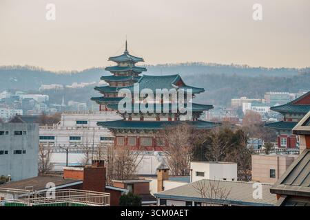 Vue surélevée de la pagode du Musée folklorique national de Corée avec son toit en tuiles bleues, s'élevant au-dessus des bâtiments urbains de Séoul et des collines lointaines. Banque D'Images