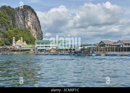 PHUKET, THAÏLANDE - 12 NOVEMBRE 2017 : pittoresque village aquatique avec des maisons sur pilotis et des falaises rocheuses sous le ciel bleu. Banque D'Images