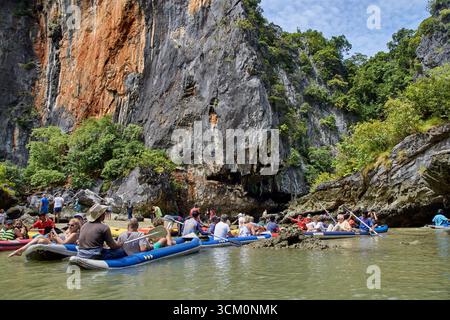 PHUKET, THAÏLANDE - 12 NOVEMBRE 2017 : touristes explorant les falaises de calcaire pittoresques sur des kayaks gonflables dans les eaux tropicales. Banque D'Images