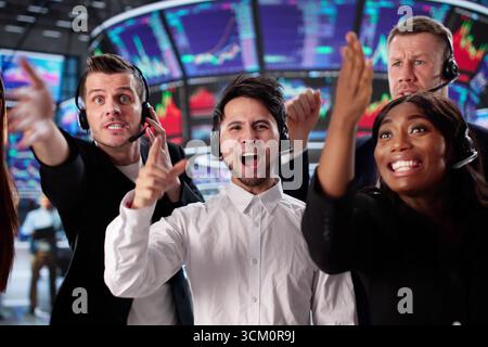 Hommes d'affaires excités négociant des actions sur American Exchange, Various Group Celebrating Win. Banque D'Images