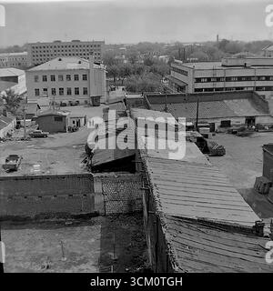 Les coulisses d'une reconstruction majeure : la vie dans les cours derrière la place centrale de Sloviansk, 1975-1976. La photo capture le mélange chaotique de la vie résidentielle, avec notamment un terrain de jeu avec des gazebos et une voiture soviétique Zhiguli, qui se poursuit au milieu du grand projet de rénovation de la ville. Cette photographie reflète le contraste saisissant entre le centre-ville cérémoniel et la vie quotidienne authentique de ses habitants, symbolisant le monde paisible et multiforme de la région du Donbass, un monde qui existait bien avant les événements tragiques de l'avenir Banque D'Images