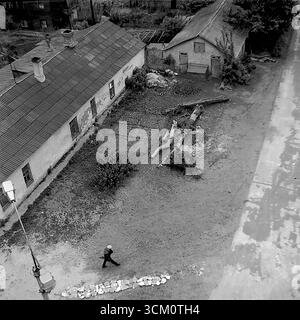Les coulisses d'un grand projet de reconstruction : cours intérieures chaotiques et secteur du logement privé derrière la place centrale de Sloviansk, 1975-1976. Le cliché capture de vieilles maisons destinées à la démolition, des hangars, des débris. Cette image reflète le processus de déminage du site pour la rénovation urbaine, symbolisant une époque révolue sacrifiée pour la nouvelle vision monumentale d'une ville soviétique, et documente la vie complexe mais paisible dans le Donbass pendant cette période Banque D'Images