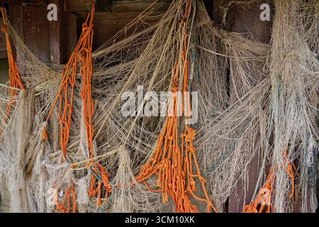 Gros plan détaillé de vieux filets de pêche enchevêtrés accrochés à un mur en bois. La composition capture la texture, les détails Banque D'Images