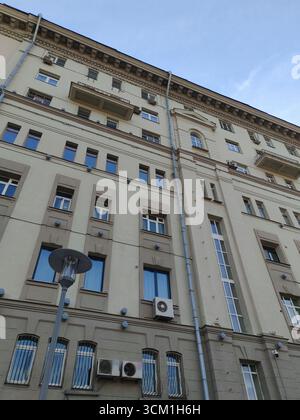 Un immeuble urbain avec plusieurs petits balcons, de grandes fenêtres et des unités de climatisation sur une façade gris clair. L'image souligne Banque D'Images