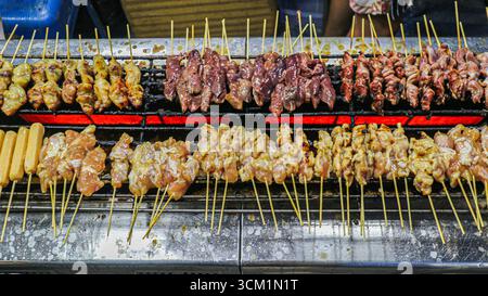 Brochettes thaïlandaises de porc, intestin de poulet et saucisses grillées au charbon de bois. Cuisine de rue authentique avec saveur fumée et tradition culinaire locale. Banque D'Images