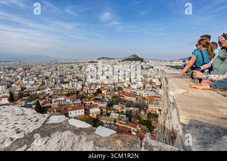 Touristes au point de vue de la colline Acropolis surplombant la ville d'Athènes, Grèce, par une journée ensoleillée. Vue sur les gratte-ciel urbains, la métropole et la ville. Banque D'Images