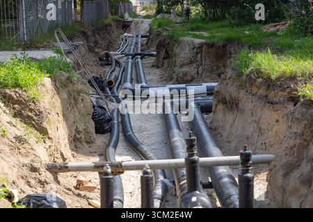 Chantier de construction urbain avec de grandes conduites d'eau noire posées dans une tranchée pendant la réparation et le remplacement des infrastructures de la ville Banque D'Images