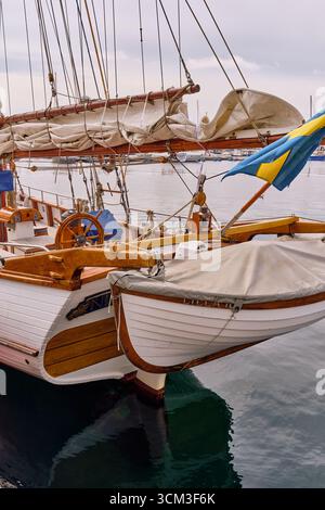Helsingborg, Suède ; 12 août 2025 : poupe traditionnelle de yacht en bois avec drapeau suédois et canot dans le port de Helsingborg. Banque D'Images