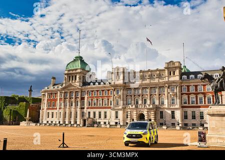 Une camionnette de police est garée devant un grand bâtiment en briques avec un dôme vert, sous un ciel nuageux à Londres, au Royaume-Uni. Banque D'Images