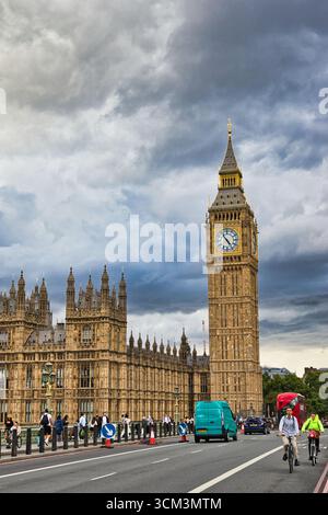 Les chambres du Parlement et Big Ben sont vues depuis un pont sous un ciel spectaculaire et nuageux, avec la circulation et les piétons présents à Londres, au Royaume-Uni. Banque D'Images