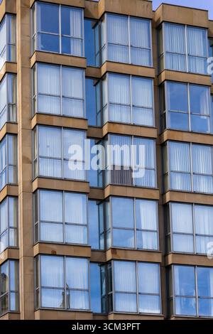 Une vue rapprochée d'une façade de bâtiment moderne avec un motif répétitif de grandes fenêtres encadrées par des panneaux de pierre tan à Newcastle upon Tyne, Royaume-Uni. Banque D'Images