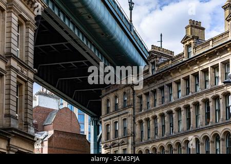 Un grand pont vert enjambe des bâtiments historiques en pierre et des structures en briques sous un ciel nuageux à Newcastle upon Tyne, au Royaume-Uni. Banque D'Images