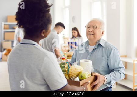 Giving Help, jeune groupe bénévole travaillant dans la fondation caritative alimentaire, faire un don aux vieux nécessiteux Banque D'Images