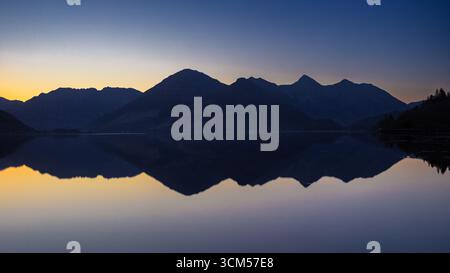 Vue sur le Loch Duich de la silhouette de la chaîne de montagnes Five Sisters au lever du soleil. Les montagnes se reflètent dans l'eau. Banque D'Images