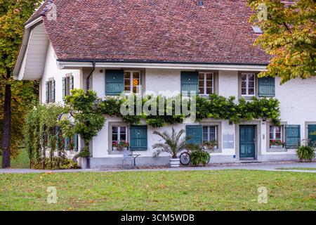 Belle maison de campagne avec une verdure vibrante et des fenêtres accueillantes, situé dans un paysage tranquille, idéal pour les amateurs de voyage à la recherche paisible re Banque D'Images