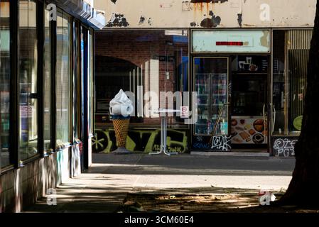Un cornet de glace original et surdimensionné sur un trottoir ensoleillé du Kreuzberg de Berlin. La devanture de magasin recouverte de graffitis et altérée capture un authentique a Banque D'Images