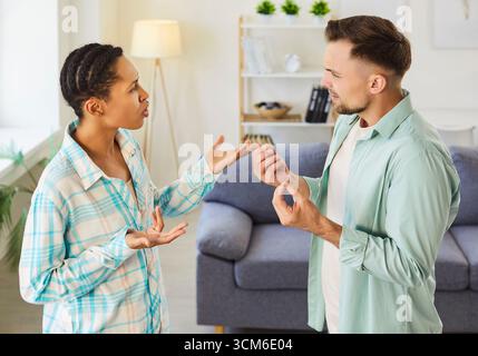 Jeune couple diversifié homme et femme debout à la maison et se disputant criant en querelle. Banque D'Images