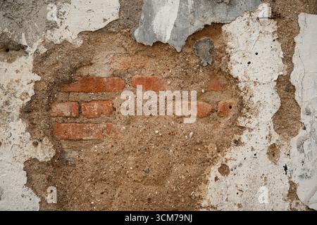 Vue rapprochée d'un mur altéré montrant des briques et du plâtre exposés Banque D'Images