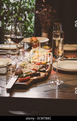 Un élégant plateau de charcuterie qui présente du vin et une variété de légumes frais Banque D'Images