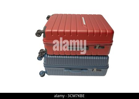 Valise rouge empilée sur une valise bleue, vue de côté. Parfait pour voyager avec style et stabilité. Valise de voyage isolée sur fond blanc Banque D'Images