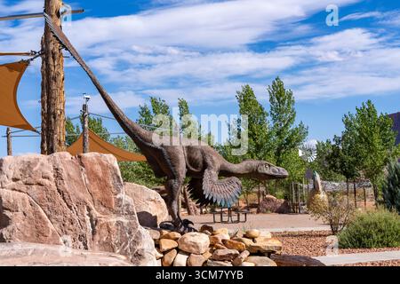 Réplique grandeur nature d'un dinosaure rapace droméosauridé sur une chute d'eau au Moab Giants Dinosaur Park, Moab, Utah. Banque D'Images