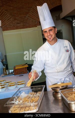 Un chef souriant expose un bouquet de pâtes artisanales dans la cuisine d'un restaurant à Rione Terra, Pozzuoli. Banque D'Images