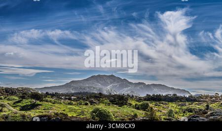Une montagne pittoresque sous un ciel spectaculaire, entourée d'une verdure vibrante. Idéal pour les thèmes de la paix, du paysage et de la nature intacte. Banque D'Images