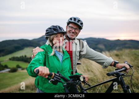 Couple plus âgé faisant du vélo ensemble dans la nature, souriant et profitant de l'aventure en plein air. Activité automnale. Banque D'Images