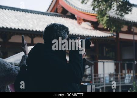 Un photographe capture les détails de l'architecture du temple au Tōdai-ji à Nara tandis qu'un autre visiteur prend une photo avec un téléphone. Banque D'Images