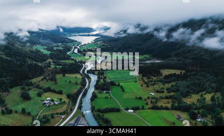 Découvrez la beauté époustouflante de Stryn, en Norvège, avec ses collines verdoyantes, ses rivières sinueuses et ses nuages spectaculaires. Le paysage vibrant invite à l'exploration, parfait pour les amoureux de la nature. Banque D'Images