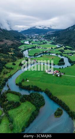 Perspective aérienne à couper le souffle de Stryn, en Norvège, révélant des champs verdoyants et des rivières sinueuses sous un ciel nuageux. Ce paysage époustouflant capture l'essence de la nature norvégienne. Banque D'Images