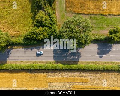 La voiture se déplace le long d'une route rurale entre les champs de terres agricoles en Angleterre Banque D'Images