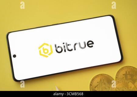 Dhaka, Bangladesh- 26 août 2025 : logo Bitrue sur l'écran du smartphone près de Bitcoin coin et QR code sur fond Banque D'Images