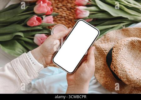 Téléphone portable et fleurs de printemps tulipes roses sur le fond rose. Thème de l'amour, la fête des mères, la journée des femmes à plat Banque D'Images