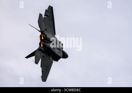 Le chasseur furtif F-22 Raptor de l'armée de l'air des États-Unis se déplace en vol avec deux post-brûleurs brillants contre un ciel nuageux. Banque D'Images