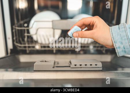 Capsule lave-vaisselle, tablettes lave-vaisselle femme met la capsule dans le lave-vaisselle. Banque D'Images