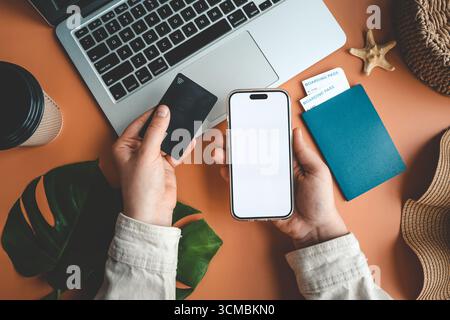 Téléphone avec un écran isolé dans les mains et une carte de crédit, le concept de vacances et de voyage. Banque D'Images