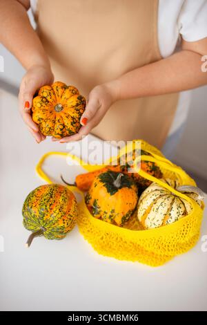 Décoration saisonnière – citrouilles dans un sac écologique sur la table Banque D'Images